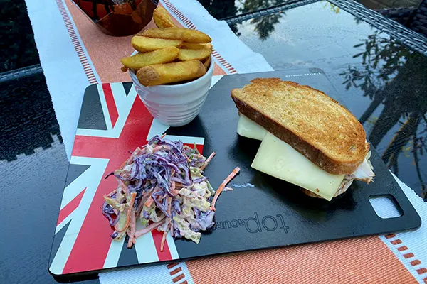 A sandwich served with a side of chips and salad.